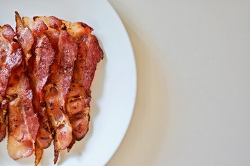 Fried bacon on the white plate on the white table 