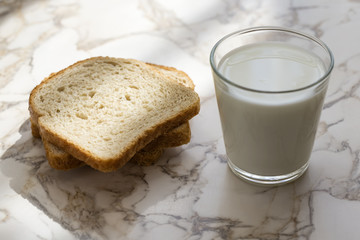 A Glass milk with bread slice on wood