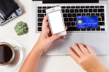 On-line shopping concept - desktop with laptop, credit card and hands holging phone