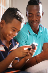 Young Man Explaining Mobile Phone Internet To Son At Home
