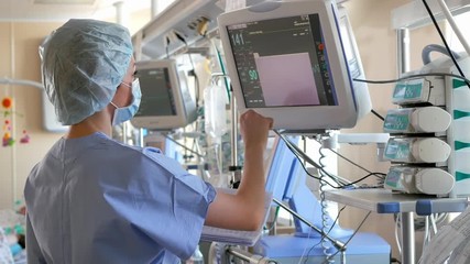 Doctor changes data on the monitor's screen in intensive care unit - Powered by Adobe