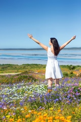 Woman in white dress enjoying the fresh spring day with arms outstretched