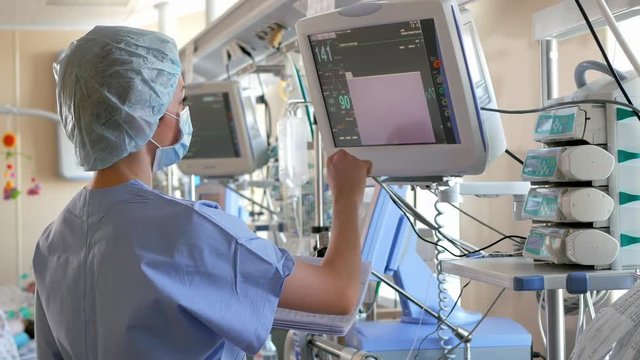 Doctor changes data on the monitor's screen in intensive care unit