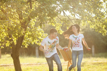 Fototapeta premium Young man and woman having fun outdoors. Pretty couple smiling and enjoing open air. Handsome guy running after beautiful woman and smiling taking her by the hand