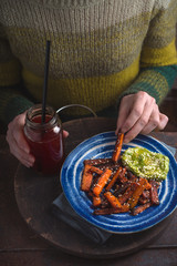 Woman in a green sweater eating fried carrot copy space