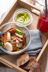 Salad, sauce, avocado, cranberry drink in a wooden box