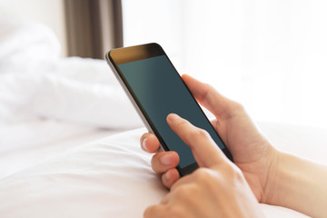 Hand using Smart phone on bed