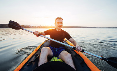 man floating on lake in a kayak at fantastic sunset.