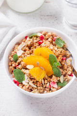 Healthy breakfast - plate of granola with orange slices, mint leaves and seeds close up