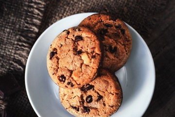 Chocolate chip cookies on white plate dark old wooden table with place for text.,  freshly baked. Selective Focus with Copy space..