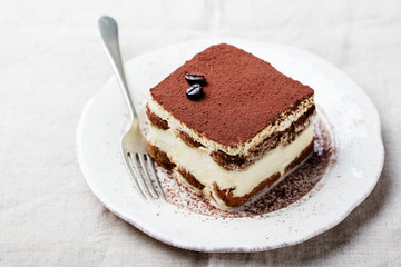 Tiramisu, traditional Italian dessert on a white plate. Copy space.