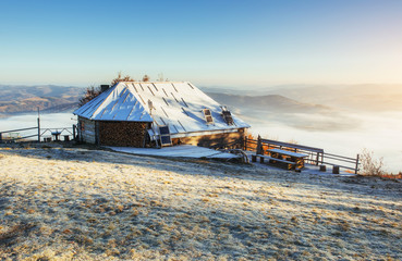 Cabin in the mountains in winter. Mysterious fog. In anticipatio