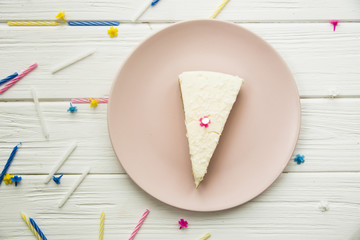 piece of birthday cake for my birthday with a candle on a pink plate on a white wooden table