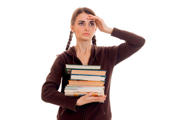 tired smart student girl in brown sport clothes with a lot of books in her hands posing isolated on white background