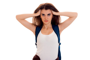 anfry smart student girl in brown sport clothes with backpack on her shoulders looking at the camera with hands on her head isolated on white background