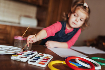 Fototapeta premium Cute little girl, adorable preschooler painting with watercolors