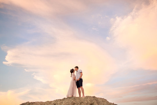 Happy couple kissing on sand mountain on sky background. Honeymoon concept