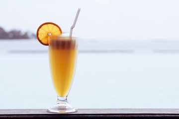 Yellow cocktail drink on wood table in twilight sea and sky background