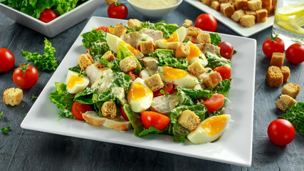 Fresh healthy Caesar salad with chicken, eggs, tomatoes, Cheese and Croutons on white plate