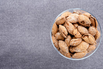 almond on glass plate on dark grey linen napkin background, top view on right side