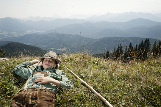 Germany, Bavaria, Boy in traditional clothing sleeps in the mountains