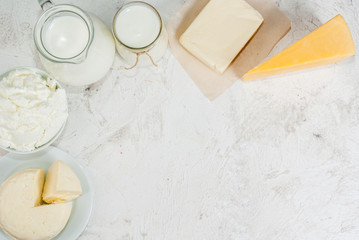 Selection of organic farming household dairy products - milk, cream (yogurt), cheese, cottage cheese, white stone concrete table. Copy space top view