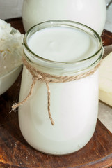Selection of organic farming household dairy products - milk, cream (yogurt), cheese, cottage cheese, white stone concrete table.