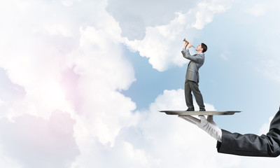 Obraz premium Businessman on metal tray playing fife against blue sky background