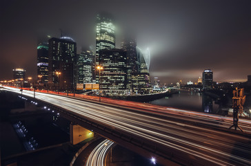 Skyscrapers of Moscow City and night traffic in the fog. Long exposure. Big city lights. Modern Moscow architecture.