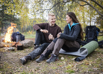 Man Grinding Coffee While Looking At Woman During Camping