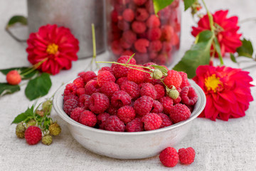 Fresh raspberry in a bowl and flowers on old  background in rustic style, selective focus.