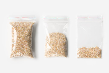 Set of three EMPTY, HALF AND FULL Plastic transparent zipper bag with raw wheat grits isolated on white. Vacuum package mockup with red clip. Concept.