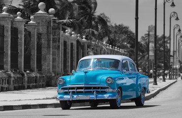Blauer Oldtimer fährt auf der berühmten Promenade Malecon in Havanna Kuba - Serie Kuba Reportage - teilkoloriert