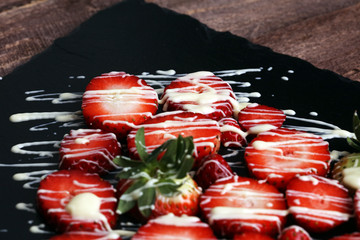 Fresh strawberries array heart shape with white nelted chocolate on old wooden background