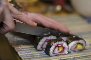 Maki sushi with cucumber and caviar being cut
