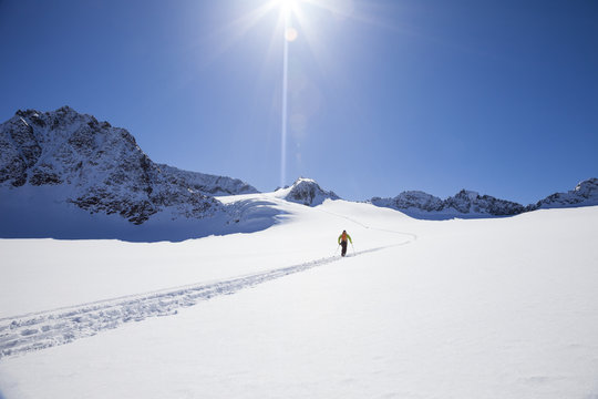 Skier walking across glacier on sunny day