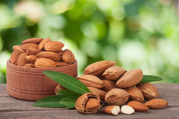 almonds in a bowl on the old wooden board with blurred garden background