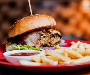 Big cheeseburger and chips on a plate.