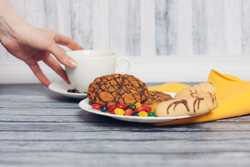 dessert in a plate and drink in a cup, female hand