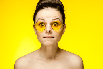 surprised woman on a yellow background, fashion glasses