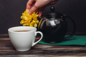 a cup with a drink, a yellow flower and a teapot