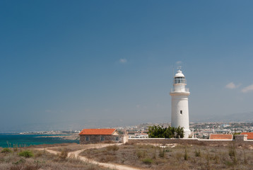 Fototapeta na wymiar White lighthouse and road on deserted seashore near Paphos city, Cyprus