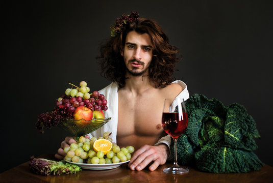 half naked curly guy sitting at a table with fruits and wine photo