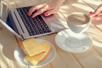 Breakfast in the morning with a computer and a Cup of coffee. The girl online. Breakfast before work. Business of the house.