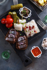 Traditional snacks salted herring with vegetables, onion, lard, bread, potato and two shots of vodka.