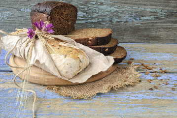 Sliced loaf of homemade bread on board on wooden background.