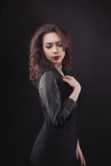 Fototapeta premium Brunette young woman with lush curly hair in black jacket