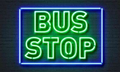 Bus stop neon sign on brick wall background.