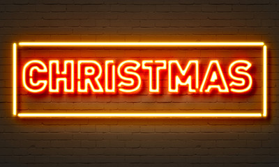Christmas neon sign on brick wall background.