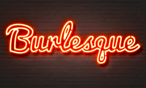 Burlesque neon sign on brick wall background.